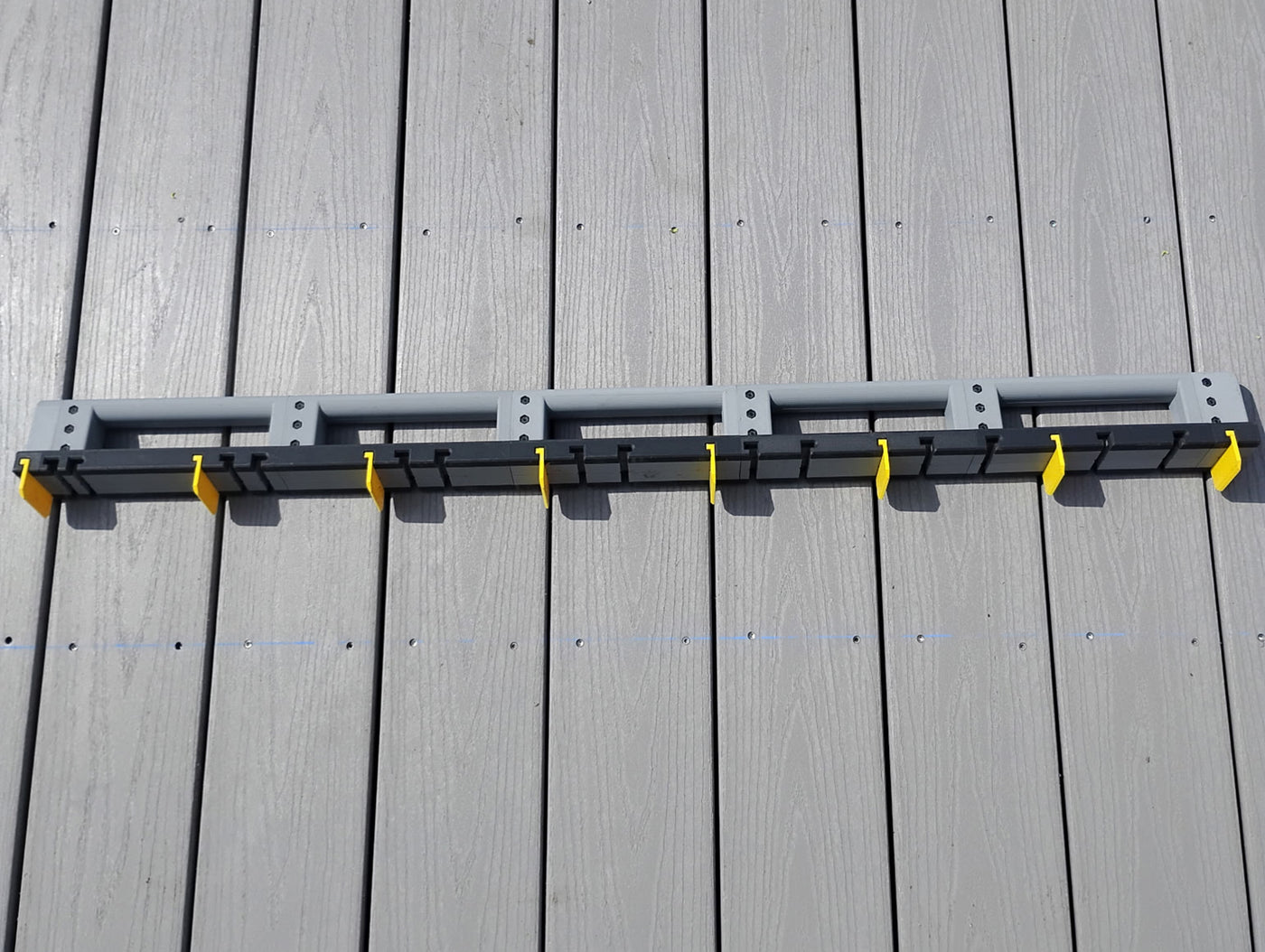 DIY builder installing decking using the Deck Board Spacer to hold spacing between boards without assistance