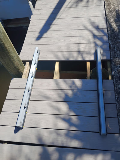Deck Board Spacer maintaining proper alignment while a deck board is skipped for a cut around a railing post."